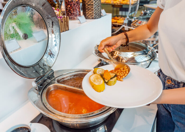 Woman choosing food in open buffet at breakfast in hotel