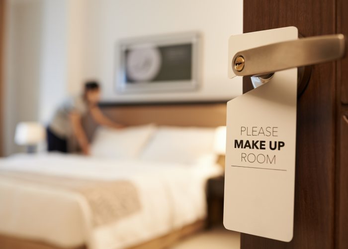 Hotel room with person making the bed in the background