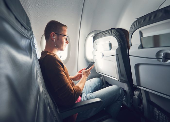 Man on airplane wearing headphones - hero