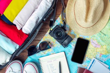 travel items check list camera shoes hat sunglasses and map are displayed on a table