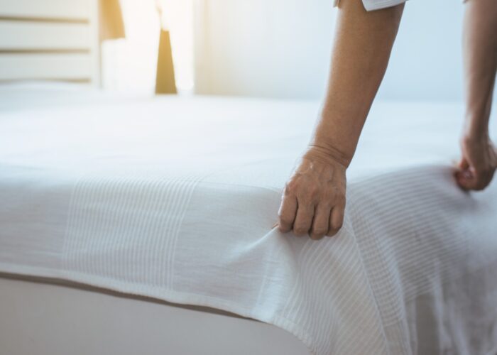 person making a bed in hotel.