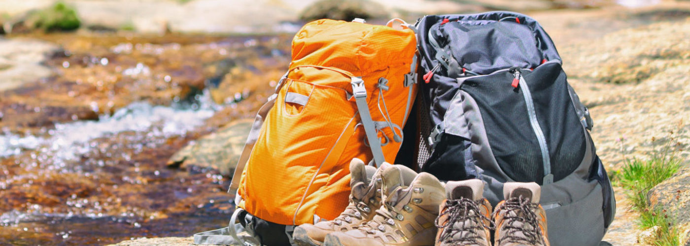 Two backpacks and some boots by a stream in nature