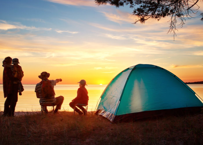 Family of four camping at sunset