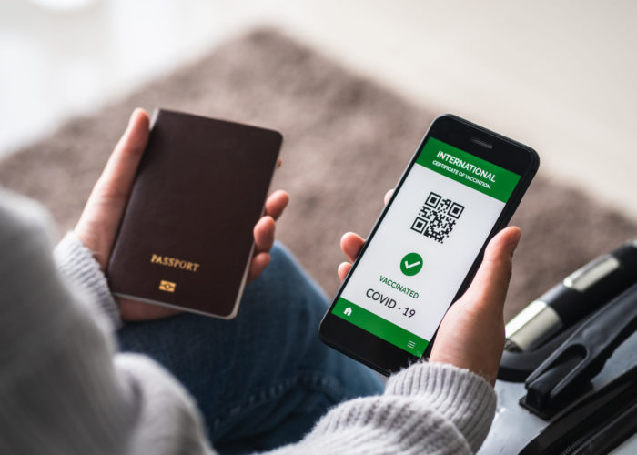 Woman holding her passport and her phone, showing a digital vaccine passport