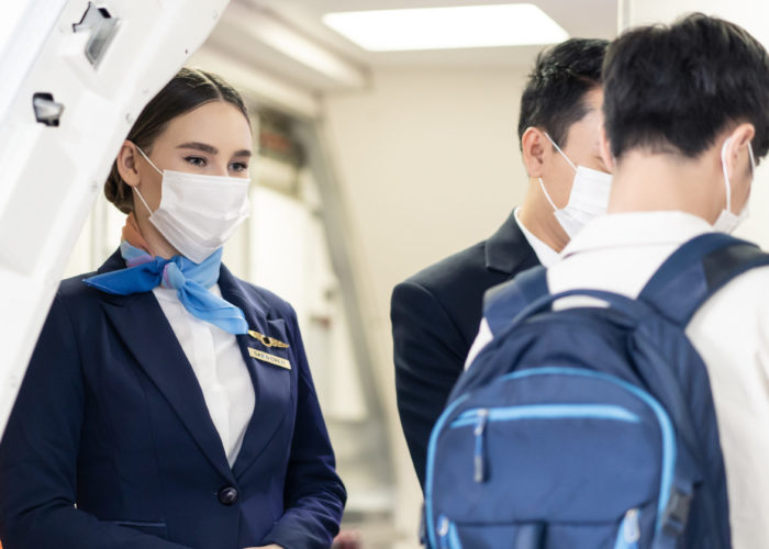 Masked flight attendant greeting passengers