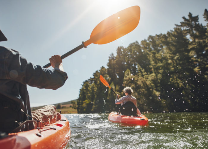 Two people kayaking on a lake on a sunny day