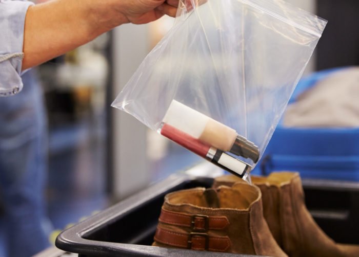 Person placing their shoes and personal items into a security bin at the airport security check