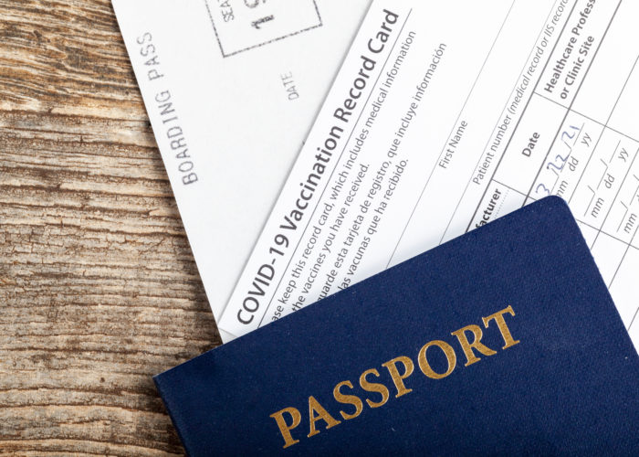 Passport, COVID vaccination card, and boarding pass on a wooden background