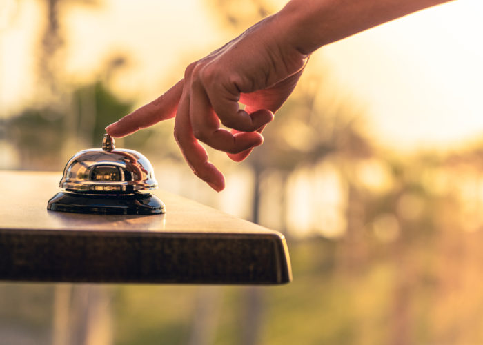 Person ringing a bell at a hotel desk for service