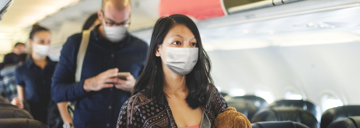 A line of people looking for their seats on the plane and wearing protective face masks