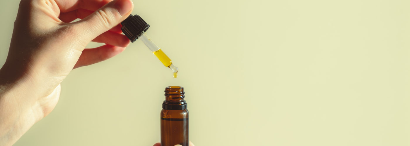 Person holding a dropper and bottle full of CBD oil