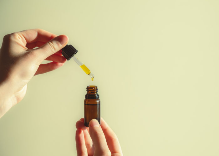Person holding a dropper and bottle full of CBD oil