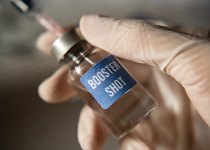 Person drawing COVID-19 vaccine from vial labeled Booster Shot