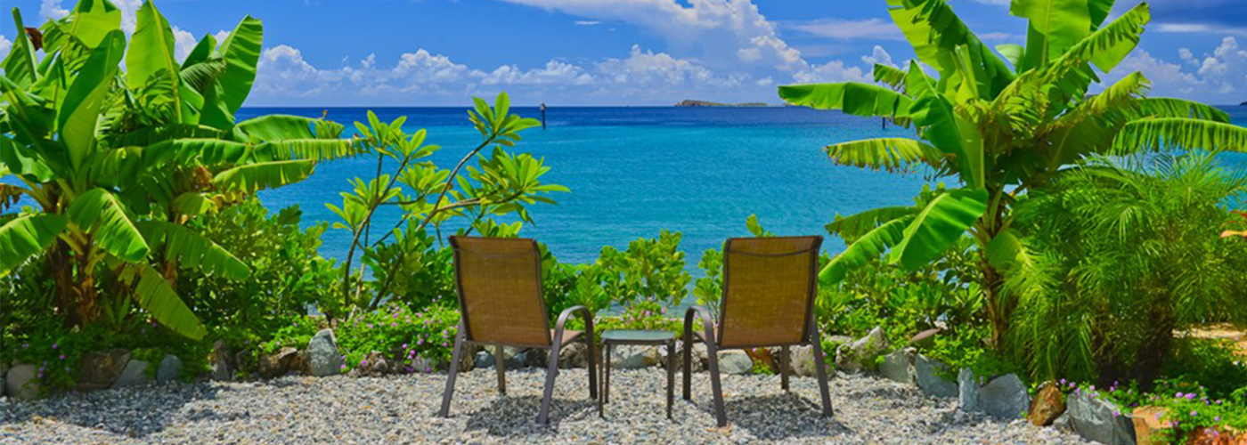 Two beach chairs overlooking the ocean and tropical greenery