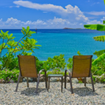 Two beach chairs overlooking the ocean and tropical greenery