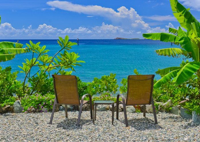 Two beach chairs overlooking the ocean and tropical greenery